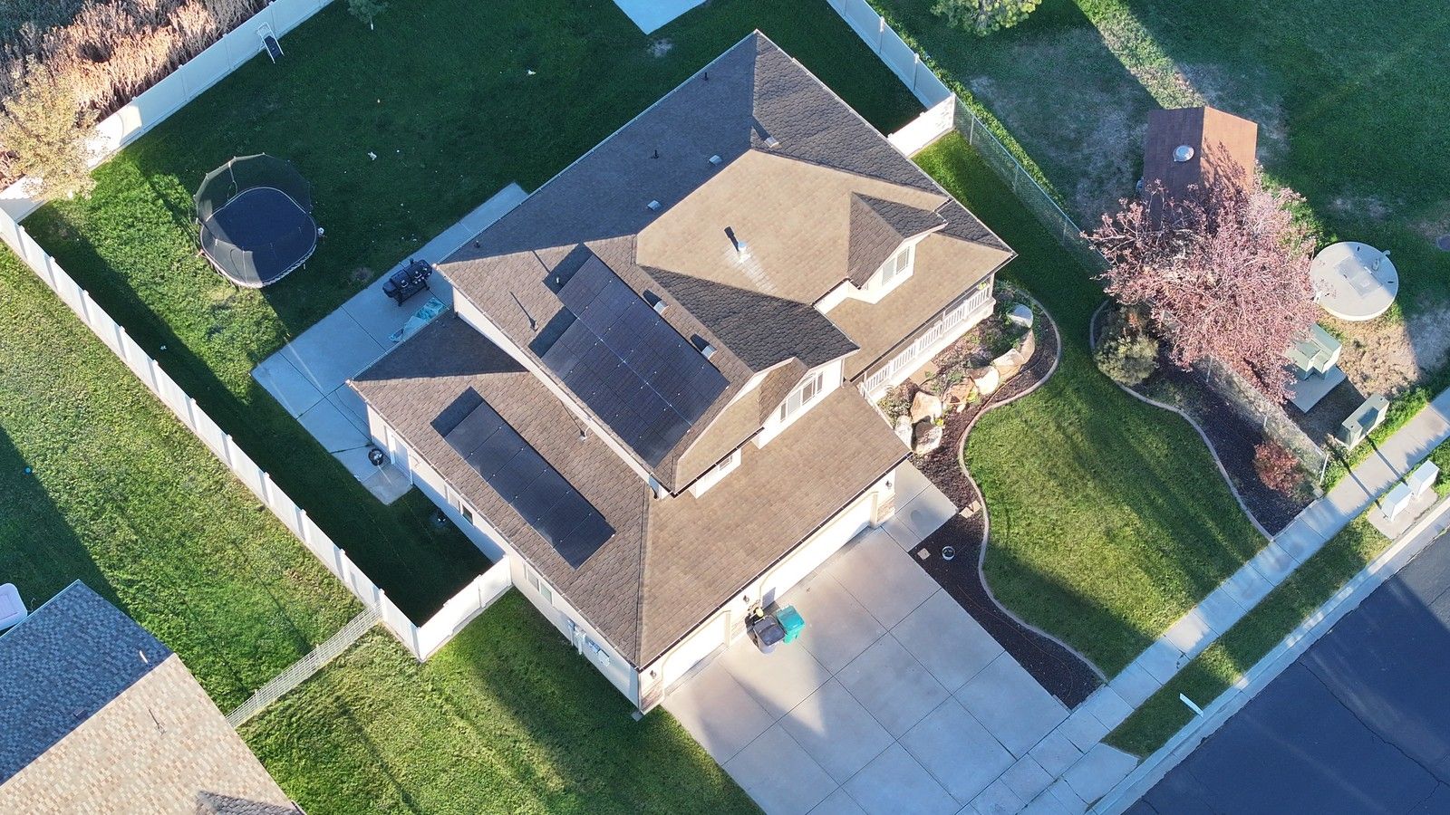 Drone view of a finished brown asphalt shingle roof with solar panels on a Utah home