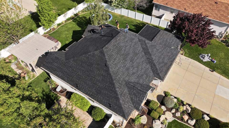 Aerial view of a home with a dark shingle roof. The NuRoof Guys.