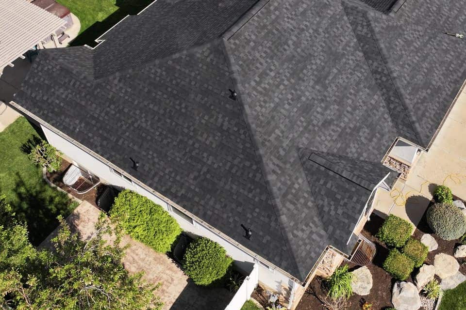 Finished charcoal asphalt shingle roof on a hip-roof home, aerial view