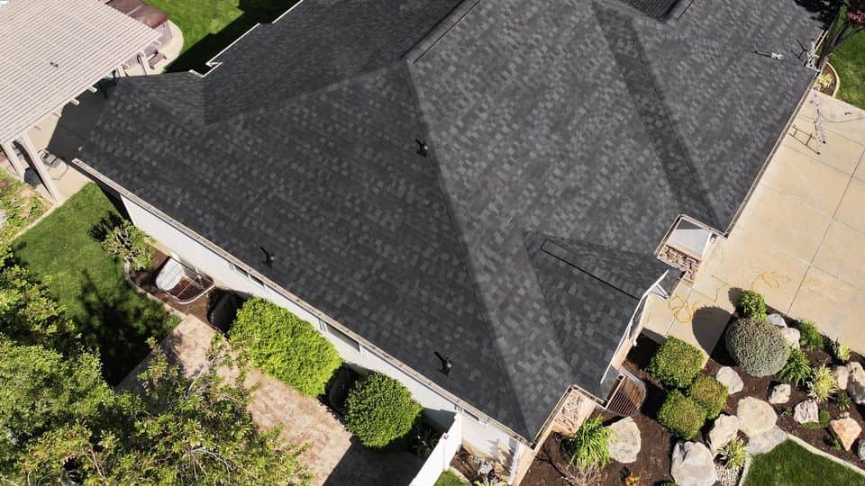 Finished charcoal asphalt shingle roof on a hip-roof home, aerial view