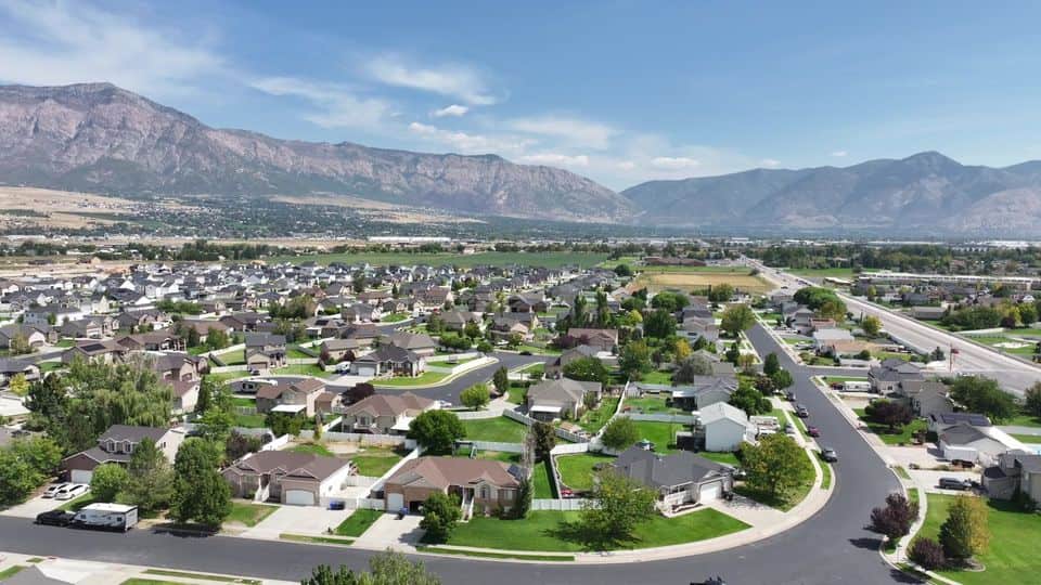 Aerial view of a valley neighborhood with the Wasatch behind. The NuRoof Guys.