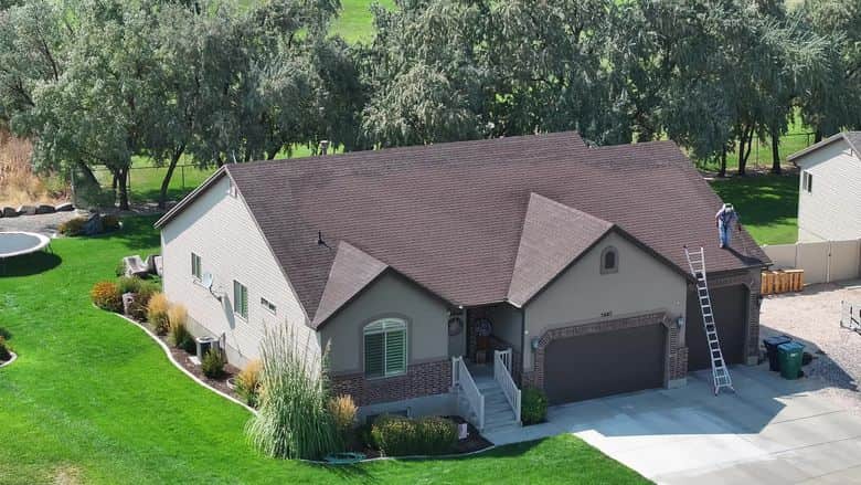 Drone orbit of a home with a brown shingle roof and a green lawn. The NuRoof Guys.