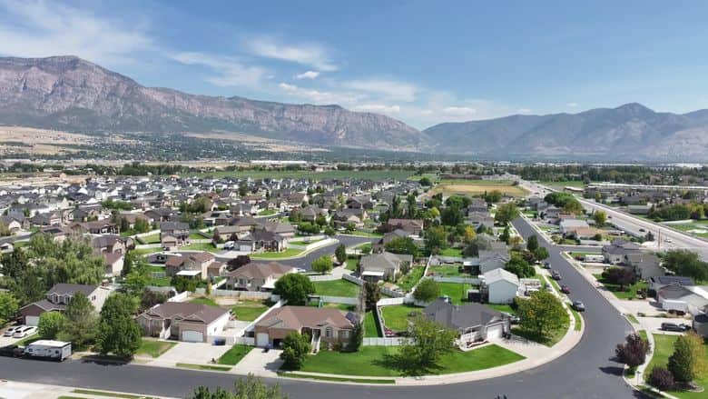 Drone view of a summer valley neighborhood with the Wasatch behind. The NuRoof Guys.